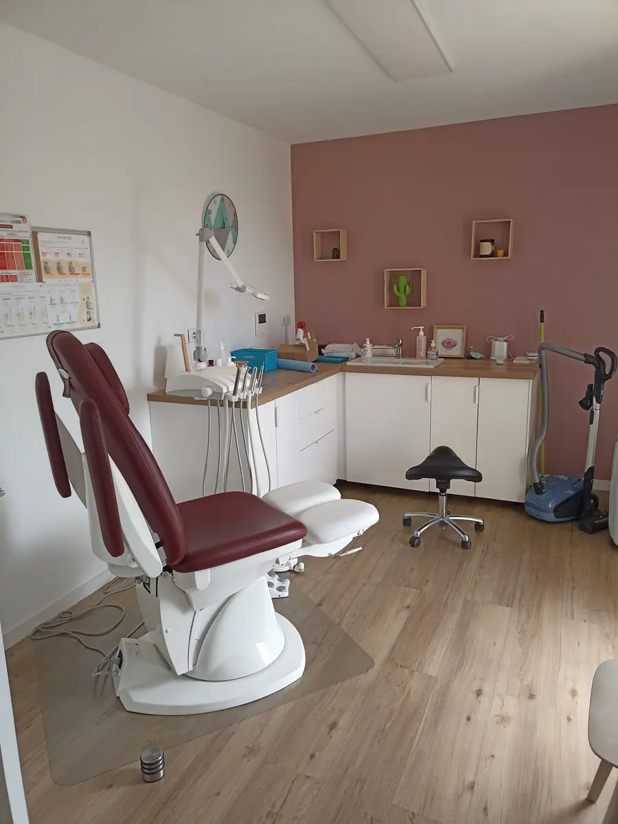 La salle de soins: fauteuil de pédicurie bordeaux, meubles blancs, mur vieux rose.